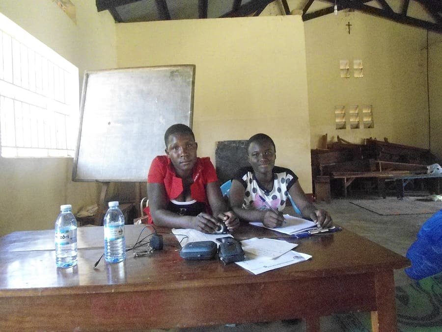 Two young facilitators recording notes at a table during a Kiyunga Social Service Centre planning meeting.