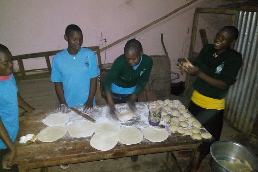 Young people preparing dough together during a Kiyunga Social Service Centre livelihood and enterprise skills training.