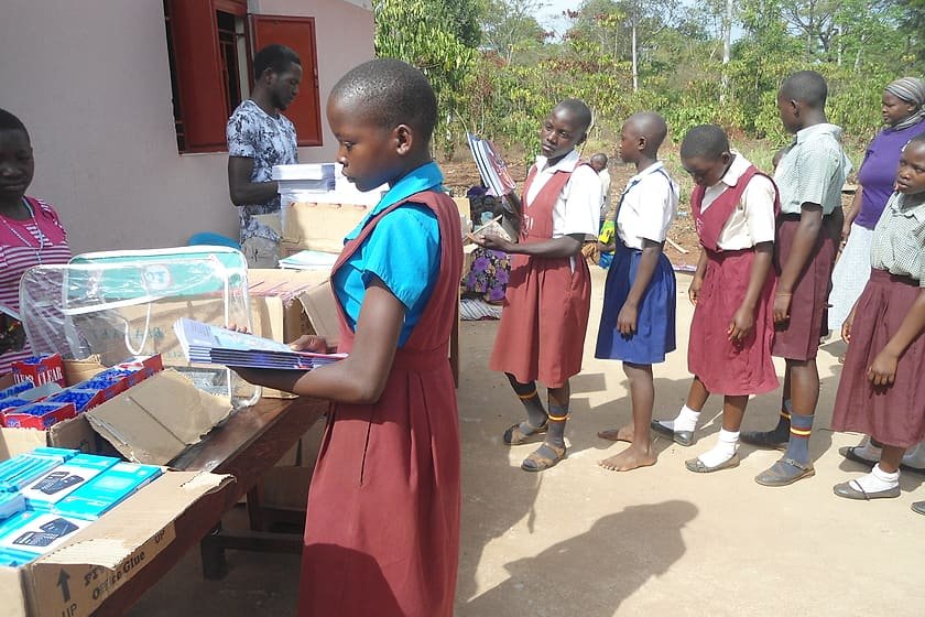 A schoolgirl carrying newly received exercise books as pupils queue for scholastic materials at a KSSC distribution.