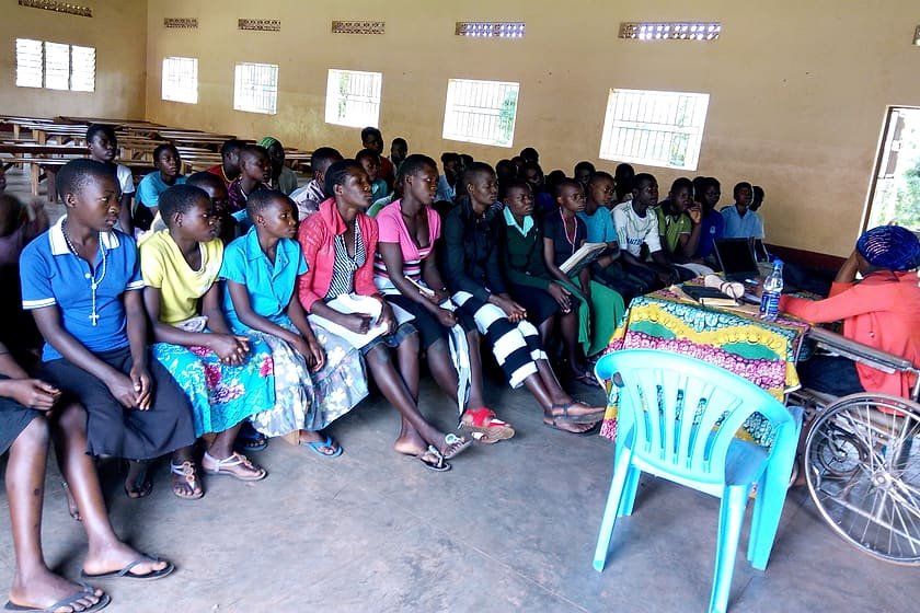 Adolescent girls and young women seated with notebooks at a Kiyunga Social Service Centre health information session.